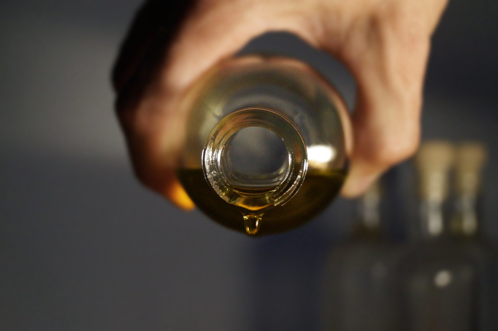 Hand Holding Bottle of Oil